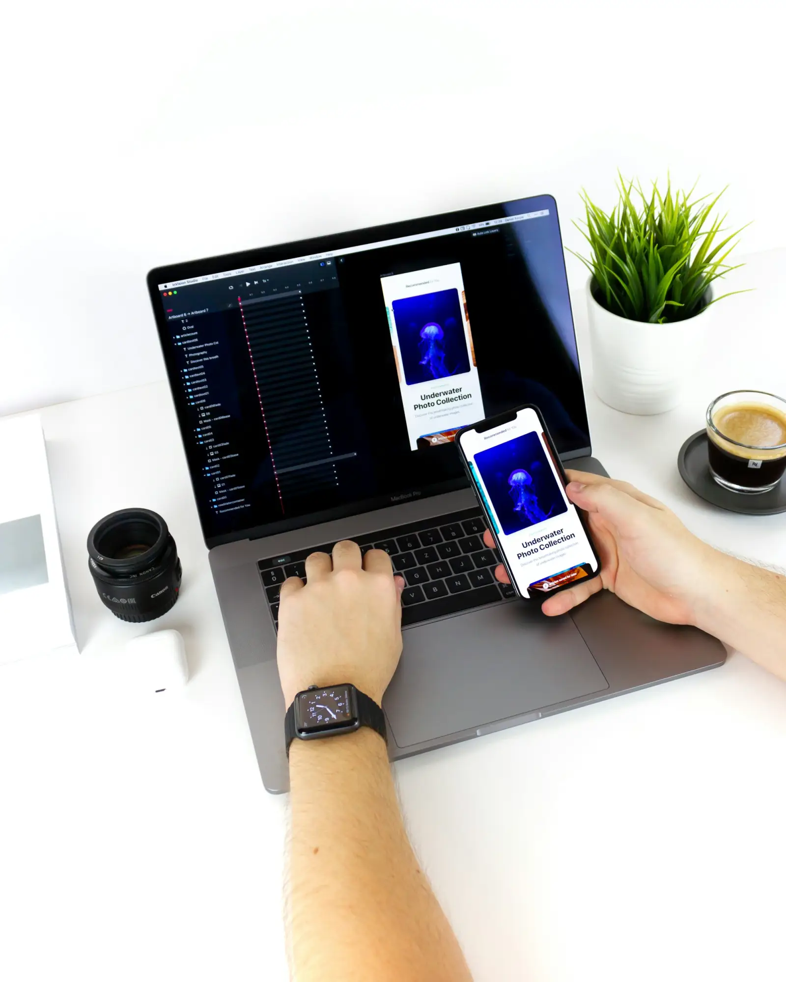 Hands using a laptop while holding a smartphone that shows the same app