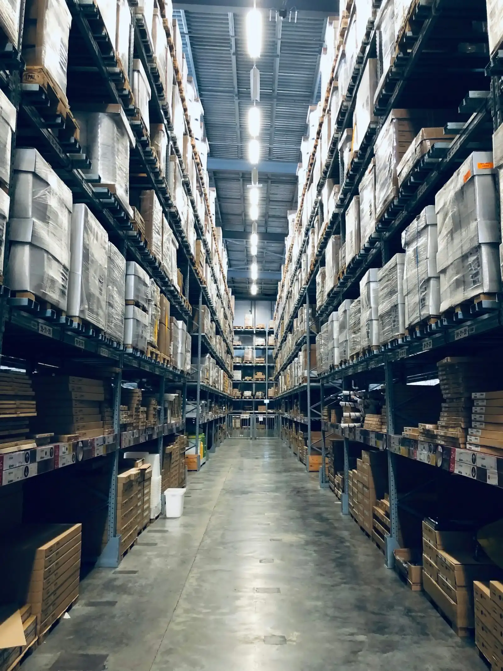 Long warehouse aisle between tall shelves stacked with boxes