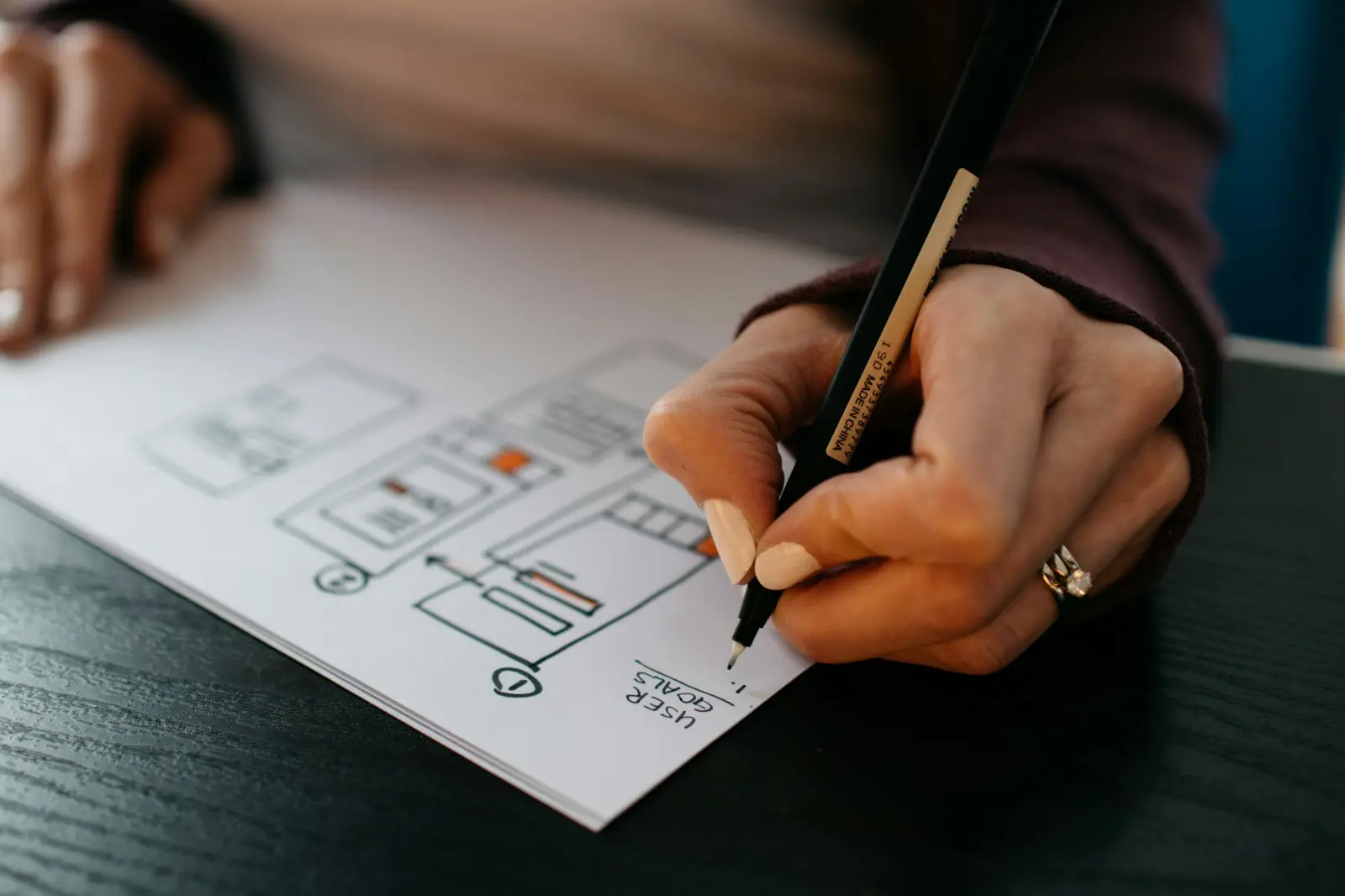 Hand sketching website wireframes on paper with a pen
